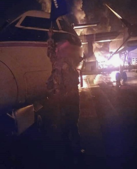 A militant waves a black flag in front of a burning DHC-8 aircraft at Manda Bay airfield in a photograph released by Al-Shabaab on 5 January. AFRICOM said at the time that six aircraft had reportedly been damaged in the attack. (Harakat al-Shabaab al-Mujahideen)