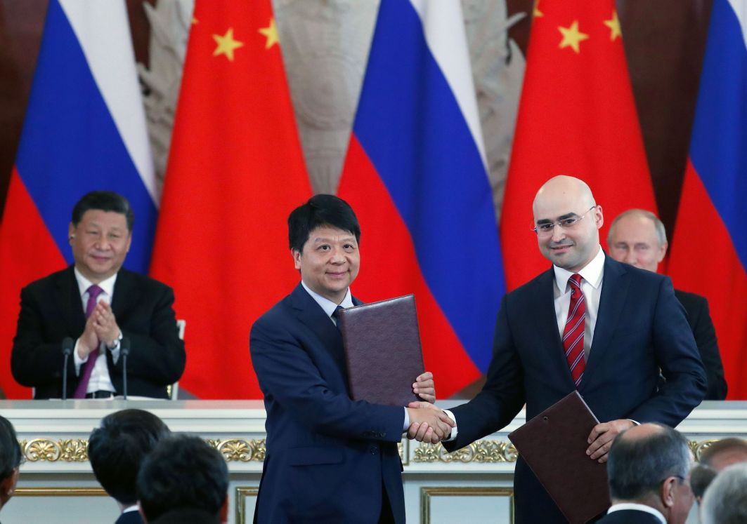 Chinese President Xi Jinping (left, rear) and Russian President Vladimir Putin (right, rear) applaud as Guo Ping (centre), Deputy Chairman of the Board and Rotating Chairman of Huawei, shakes hands with Alexei Kornya, President and CEO of Russian mobile phone operator MTS, during a signing ceremony following Chinese-Russian talks at the Kremlin in Moscow on 5 June 2019. (Maxim Shipenkov/AFP via Getty Images)